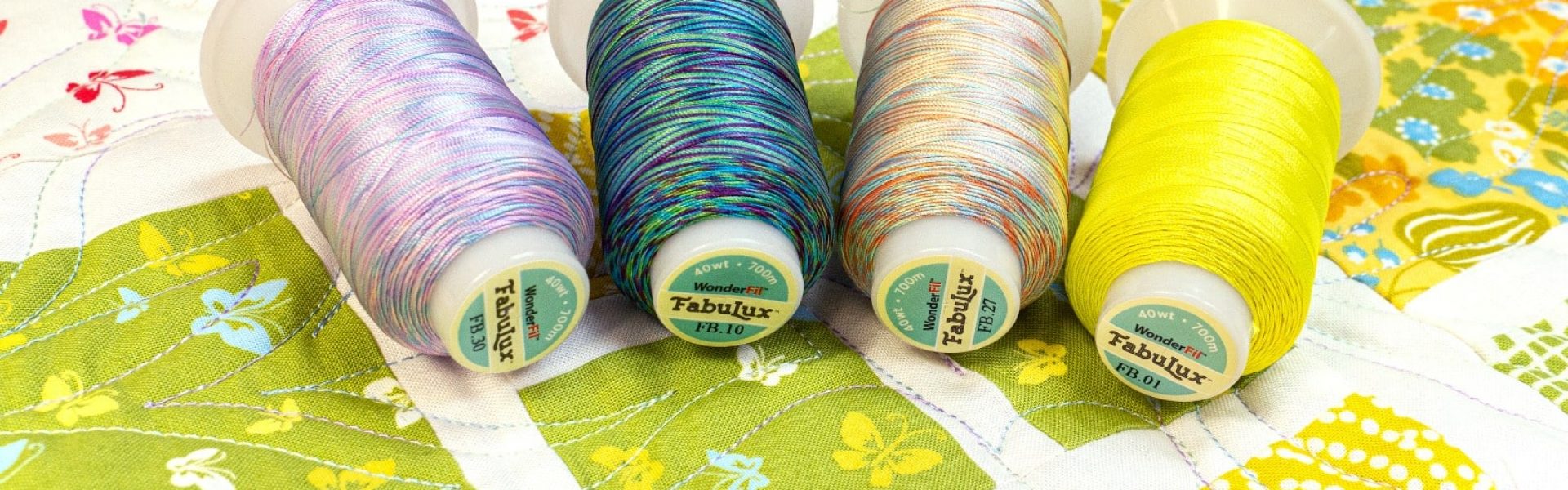 A photo of spools of FabuLux 40wt trilobal polyester thread on a quilt.